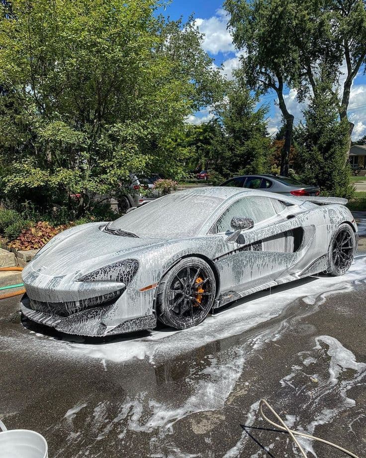 McLaren 570S being foam-washed in a residential driveway